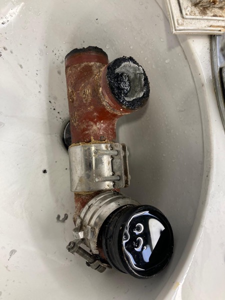 DrainFix HK 紅鑄鐵 T-fitting 完整拆解擺喺白瓷盤,stainless coupling + 黑色 rubber seal 分開排好
