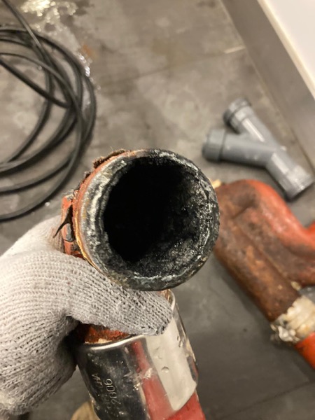 DrainFix HK 戴手套拎起一段崩咗嘅紅鑄鐵渠管末端,俾客戶睇損壞嚴重程度
